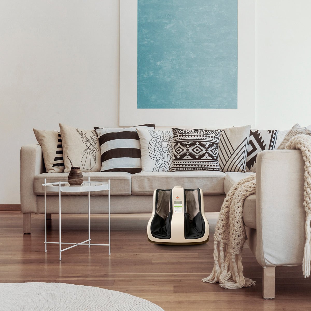 Reflex SOL Foot and Calf Massager shown in modern living room with beige couch and geometric pillows