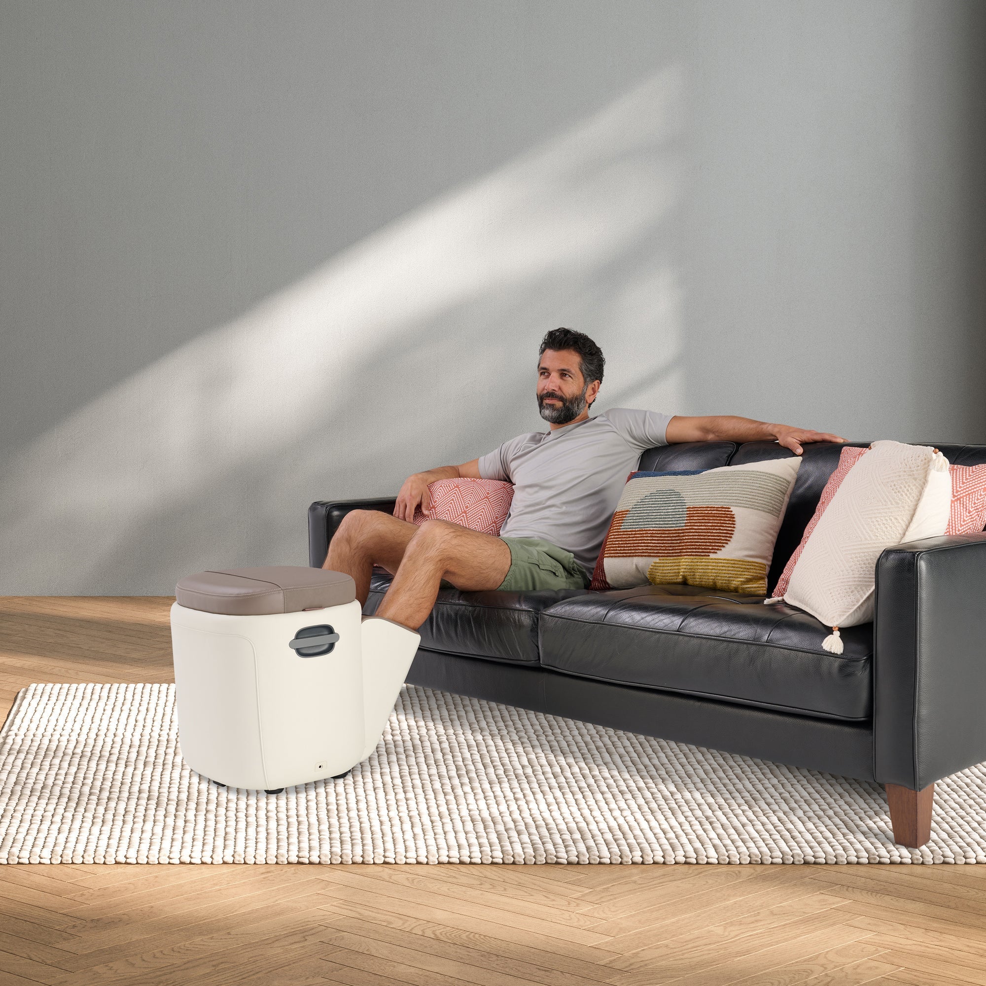 Reveal Ottoman Massager shown as stylish foot massager next to couch, demonstrating comfort and modern living room design