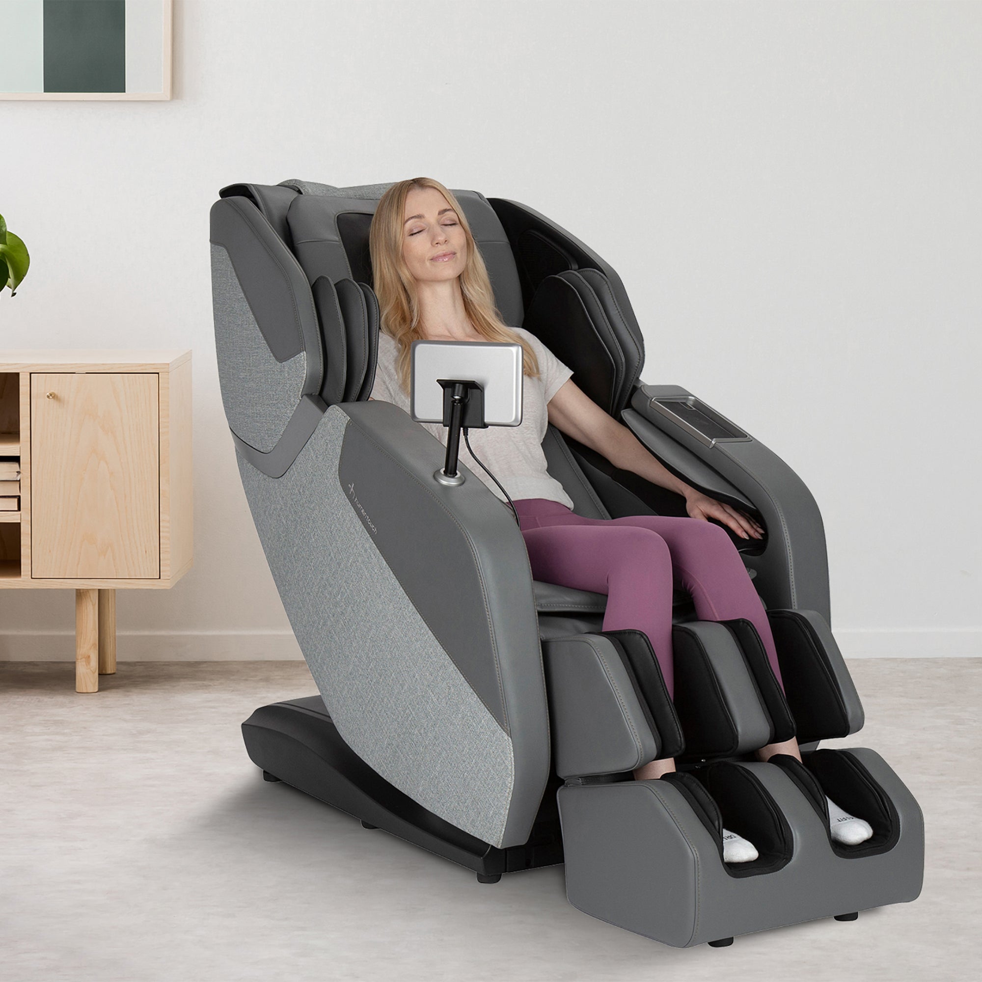 A person relaxing in the WholeBody ROVE Massage Chair, showing its gray design and full-body massage features
